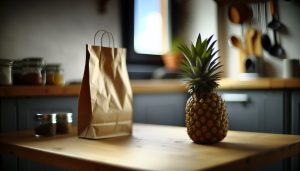 Un ananas posé sur une table de cuisine avec un sac en papier à côté.