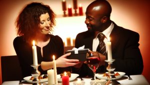 Un couple amoureux échangeant un cadeau d'anniversaire dans un cadre romantique, comme un dîner aux chandelles.
