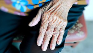 Un gros plan d'une main de femme âgée montrant des rides et des taches de vieillesse.